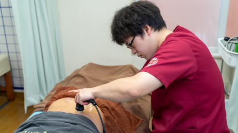 電気刺激を使用した施術をするスタッフ